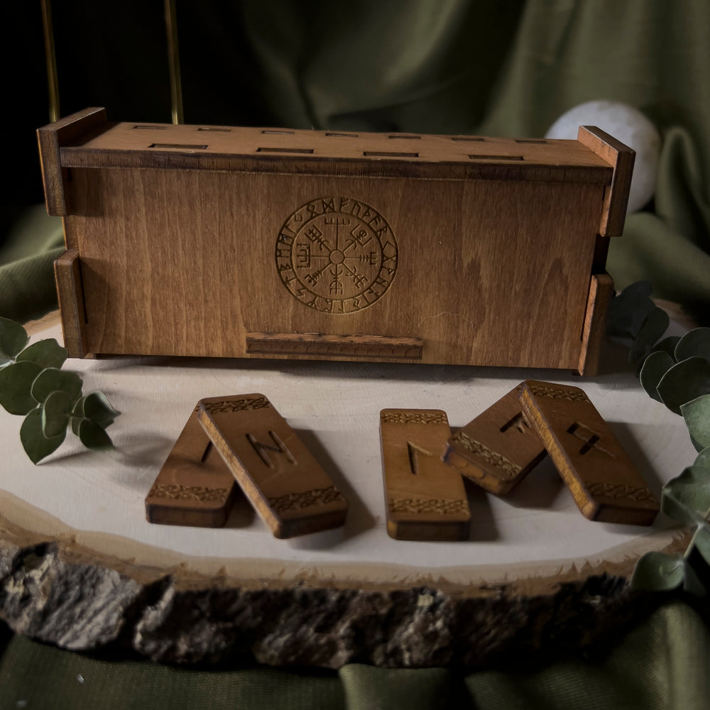 Light brown wood box with the vegvisir in the center, small wood rune staves lay in front of it, individually carved.