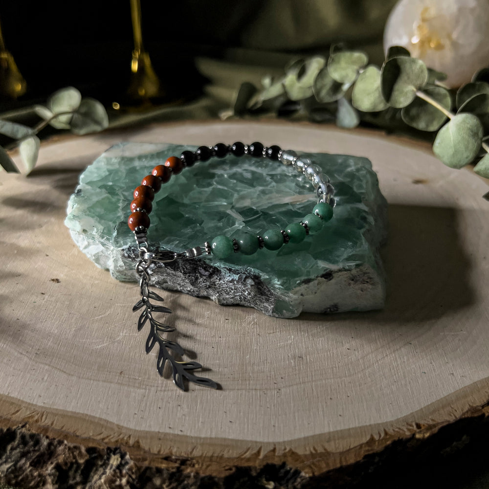 A bracelet with gemstone beads in the colors of the Palestinian flag with an olive branch charm. 